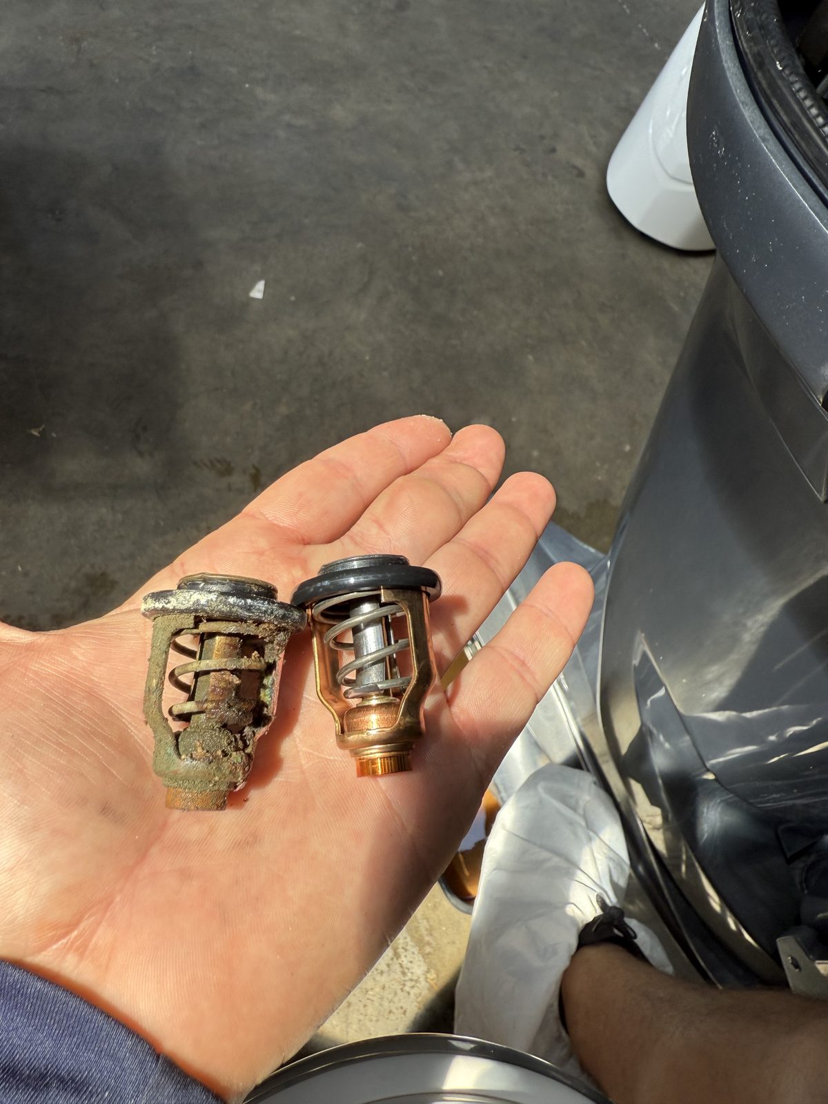 Corroded outboard thermostat next to a new replacement thermostat